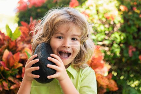 Photo for Happy child showing avocado on summer garden. Kids healthy food - Royalty Free Image