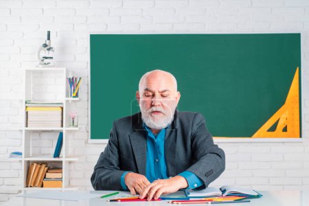 Photo for Professor in classroom at the school. A teacher who works professionally. A teacher who knows a lot. Teacher in glasses. Dear Professor. Senior teacher in classroom - Royalty Free Image