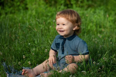 Foto de Pequeño bebé sonriente jugando en la naturaleza en la hierba verde. Niños jugando. Bebé y verano tiempo soleado - Imagen libre de derechos