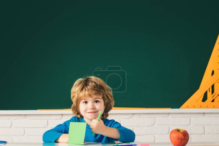 Photo for Funny child from elementary school. Children learning. Cute child boy in classroom near blackboard desk. Chalkboard copy space - Royalty Free Image