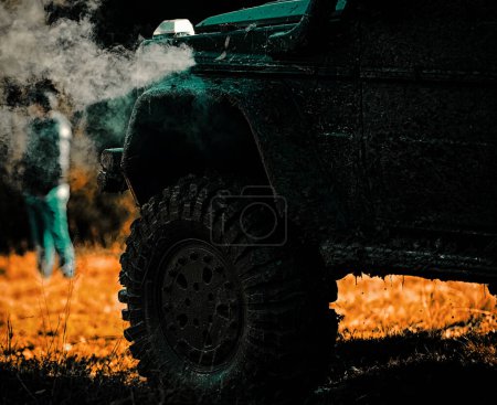 Photo for Off road sport truck between mountains landscape. Tracks on a muddy field. Bottom view to big offroad car wheel on country road and mountains backdrop - Royalty Free Image