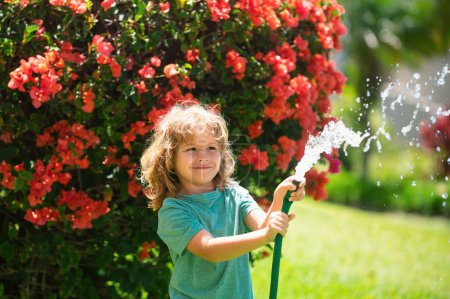 Photo for Child having fun in domestic garden. Child hold watering garden hose. Active outdoors games for kids in the backyard during harvest time - Royalty Free Image