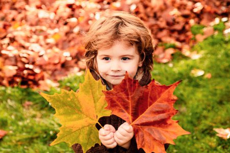 Foto de Niño con hojas de otoño. Otoño retrato al aire libre de lindo niño feliz caminando en el parque o el bosque en ropa de punto caliente - Imagen libre de derechos