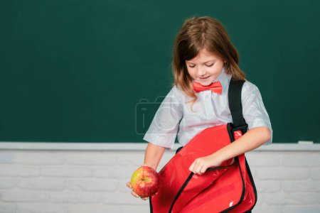 Foto de Retrato de linda, encantadora, chica con mochila en uniforme escolar en el aula. Educación y conocimiento para niños. Estudiantes niños - Imagen libre de derechos