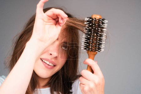 Foto de Chica triste con el pelo dañado. Tratamiento del problema de pérdida de cabello. Retrato de mujer con peine y cabello problemático - Imagen libre de derechos