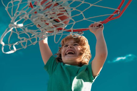Téléchargez les photos : Un drôle de gamin excité jouant au basket. Gros portrait d'enfant. Enfant drôle visage sportif - en image libre de droit
