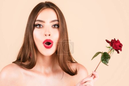 Foto de Hermosa mujer sorprendida con flor de rosa roja. Labios rojos y rosa. Chica bella. Sensual boca sexy. Cumpleaños. - Imagen libre de derechos