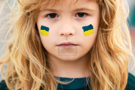 Foto de Signo de bandera ucraniana en la mejilla infantil. Crisis mundial geopolítica ucraniana. Cerca de cara de los niños - Imagen libre de derechos