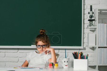 Téléchargez les photos : Les petites filles dessinent des images colorées avec des crayons de couleur dans la salle de classe de l'école. Peindre des enfants. Enfant art, créativité enfant concept - en image libre de droit