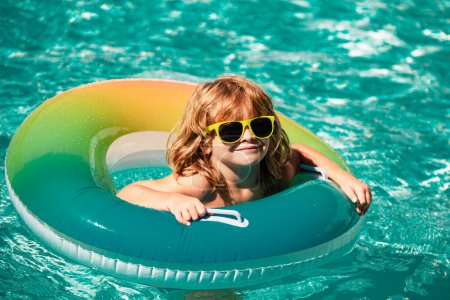 Téléchargez les photos : Enfant aux vacances d'été Aquapark Kids. Garçon dans la piscine. Garçon heureux sur le cercle en caoutchouc gonflable - en image libre de droit