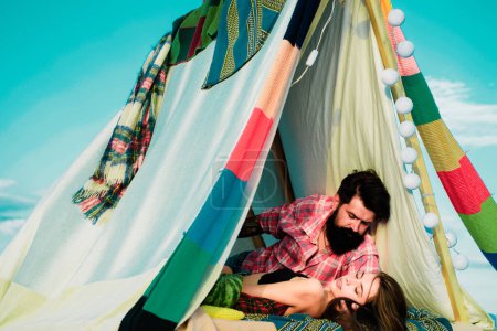 Téléchargez les photos : Couple romantique camping sur paysage printanier. Aventure pour les jeunes amateurs campeurs en tente sur la nature. Couple hipster tendre baisers dans la tente du camp - en image libre de droit