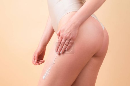 Téléchargez les photos : Crème sur les fesses sexy femme avec une peau propre et douce. Appliquer de la crème hydratante sur les jambes. Traitement cellulite ou anti cellulite. Soins du corps et concept de salon de spa - en image libre de droit