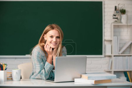 Téléchargez les photos : Étudiante travaillant sur un ordinateur portable en classe, se préparant à un examen. Creative jeune étudiante souriante utilisant un ordinateur portable - en image libre de droit