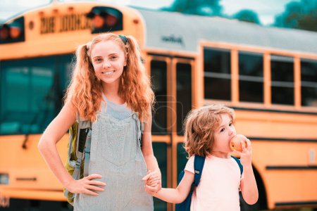 Foto de Autobús escolar y niños felices. Retrato de hermanito feliz y hermana de pie juntos frente al autobús escolar - Imagen libre de derechos