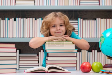 Photo for School boy with stack of books in library. Back to school. Funny little boy from elementary school with book. Education - Royalty Free Image