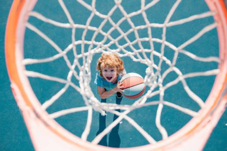 Foto de Niño sorprendido jugando baloncesto sosteniendo la pelota con la cara feliz - Imagen libre de derechos