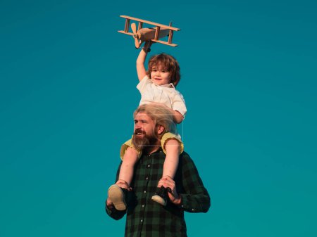 Photo for Boy with toy plane sitting on fathers shoulders. Happy father and son with airplane dreams of traveling - Royalty Free Image