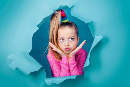 Photo for Thoughtful little girl seven years old is looking away on copy space. Interested minded kid touching chin, thinking on a blue background, Funny kid pout lips. Conceived some kind of prank, concept - Royalty Free Image