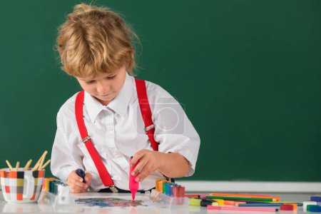 Foto de Child boy drawing cute draw using colored pencils at school or kindergarten. Childhood learning, kids artistics skills - Imagen libre de derechos