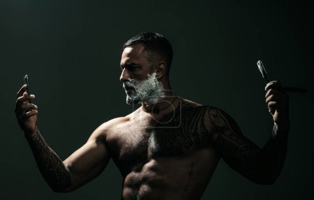Foto de Cuchilla de barbero. Cepillo de afeitar con crema de espuma. Hombre con navaja vintage. serios sexy chico afeitando barba - Imagen libre de derechos