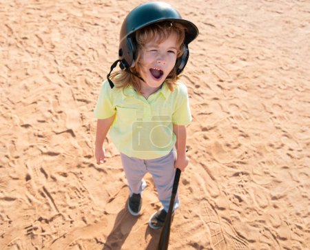 Foto de Funny jugador de béisbol de niño en casco de béisbol y bate de béisbol - Imagen libre de derechos