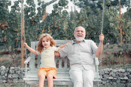 Téléchargez les photos : Grand-père et petit-fils balançant sur swing extérieur - en image libre de droit