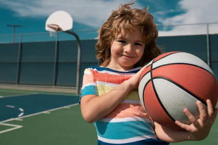 Téléchargez les photos : Petit garçon jouant au basket avec une balle de basket. Mode de vie actif des enfants. École de basket-ball - en image libre de droit