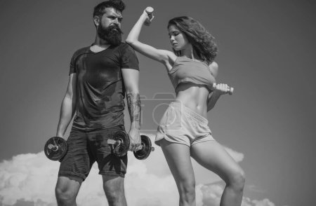 Photo for Sportive fitness couple, bearded man and sexy woman working out outdoors, sportive couple training with dumbbells - Royalty Free Image