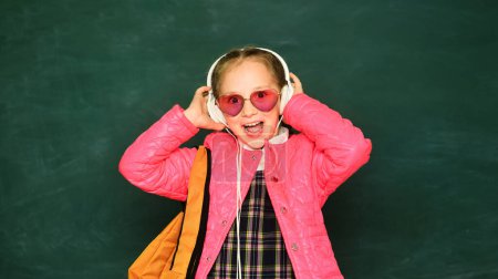 Téléchargez les photos : Adolescente écolière jeune avec port de lunettes sac à dos et écouteurs - en image libre de droit