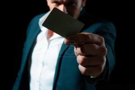Foto de La mano tiene una tarjeta de crédito. Empresario en traje de negocios paga con tarjeta de crédito - Imagen libre de derechos