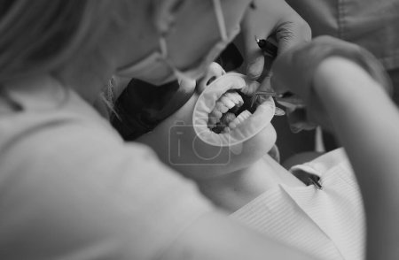 Téléchargez les photos : Portrait en gros plan d'une patiente en visite chez le dentiste pour le blanchiment des dents en clinique. Dentiste examinant les dents des patients à la clinique. Blanchiment des dents - en image libre de droit
