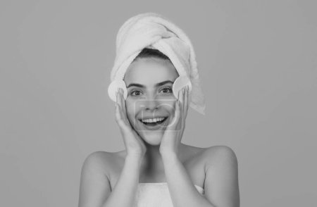 Foto de Retrato de cara de belleza. Terapia de spa, hermosa mujer en toalla tocando mejilla con esponja cuida de la piel - Imagen libre de derechos