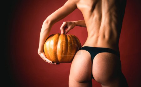 Photo for Woman posing with Pumpkin. Buttocks ass and pumpkin close-up. Huge buttocks. Great ass and pumpkin. Pumpkin - funny concept. Trick or treat - Royalty Free Image