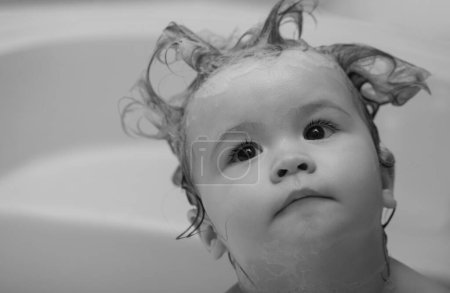 Téléchargez les photos : La petite enfant se lave les cheveux dans le bain. Enfants drôles visage gros plan - en image libre de droit