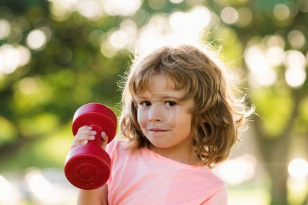Photo for Funny child sport. Kid boy with dumbbells. Kids development and healthy strong exercise. Fun child faces. Children health concept. Outside - Royalty Free Image