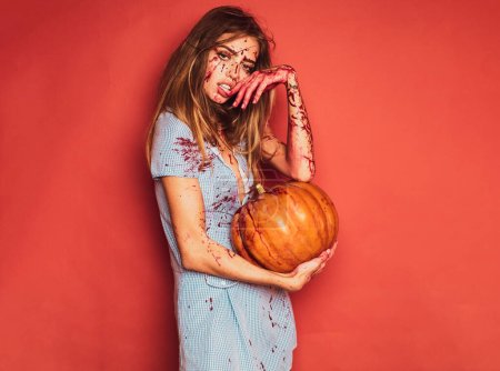 Photo for Sexy girl dress killer to Halloween festival. Halloween girl with a carved Pumpkin. Pretty young blonde woman clothed in dress with pumpkins. Sexy vampire woman with blood on her face - Royalty Free Image