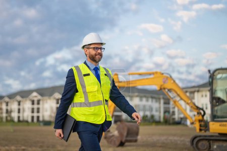 Photo for Architect at a construction site. Architect man in suit and helmet at construction site. Confident architect standing at construction. Investor or civil engineer. Outdoor portrait of hispanic - Royalty Free Image