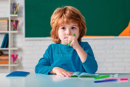 Photo for Kid is learning in class on background of blackboard. Teachers day. Talented child. Cute little preschool kid boy with teacher study in a classroom - Royalty Free Image