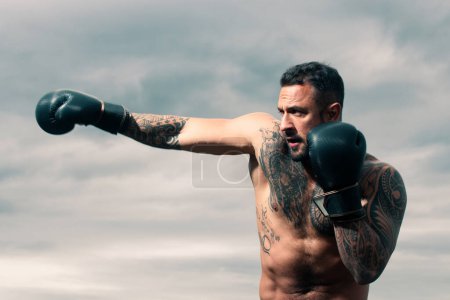 Foto de Boxeador de patadas musculares o boxeador tailandés muay. Luchador de Kickboxing en guantes de boxeo golpeando la sombra, entrenamiento para la competencia. Golpe de boxeo - Imagen libre de derechos