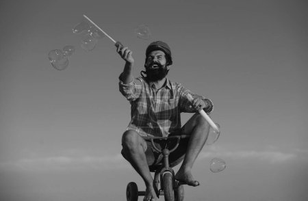 Téléchargez les photos : La mémoire de l'enfance. Portrait d'un homme barbu comme un hipster fou s'amuser avec vélo à l'extérieur - en image libre de droit