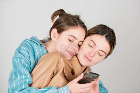 Foto de Lesbianas pareja lgbt. Retrato de dos jóvenes alegres con teléfono móvil, smartphone. Dos hermosas mujeres jóvenes con la piel perfecta en el estudio. Lgbt, tolerancia, lesbianas pareja amor - Imagen libre de derechos