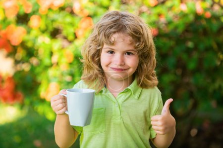 Foto de Niño bebiendo té o agua en el jardín del patio trasero. Curar a los niños y proteger la inmunidad contra el virus estacional, concepto de salud para niños - Imagen libre de derechos