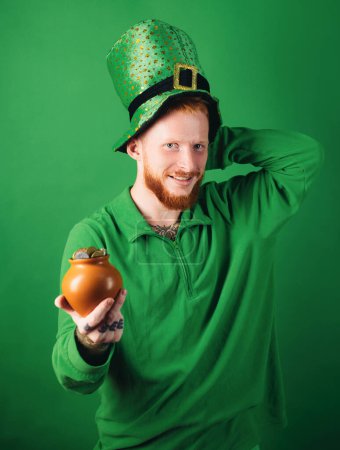 Téléchargez les photos : Happy St Patricks Day concept avec pot d'or. Charmes chanceux sur fond vert. Chapeau de lutins. Un homme sur fond vert célèbre la Saint Patricks Day - en image libre de droit
