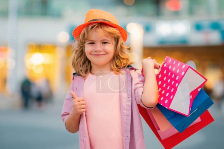 Téléchargez les photos : Enfant en shopping. Portrait d'un enfant avec des sacs à provisions. Shopping boy - en image libre de droit