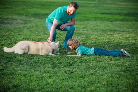 Foto de Padre e hijo jugando con el perro en el parque. Papá y el niño se divierten al aire libre - Imagen libre de derechos