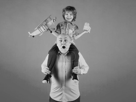 Photo for Grandson child and grandfather piggyback ride with plane and wooden toy truck. Men generation granddad and grandchild - Royalty Free Image