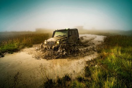 Photo for Wheel close up in a countryside landscape with a muddy road. Off-road vehicle stuck on impenetrable road after rain in the countryside - Royalty Free Image