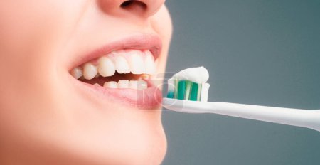 Téléchargez les photos : Close-up mouth with teeth-brush. Dental health care clinic. Close-up of a young woman is brushing her teeth. Toothbrush with toothpaste. Dental banner, copyspace - en image libre de droit