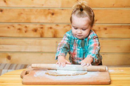Téléchargez les photos : Petit boulanger enfant à la cuisine. Bébé garçon dans la cuisine aider à cuisiner, jouer avec la farine - en image libre de droit