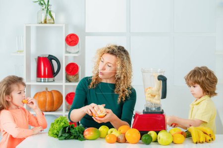 Téléchargez les photos : Portrait de famille mignonne fait jus de fruits. sur cuisine blanche. Aliments sains à la maison - en image libre de droit